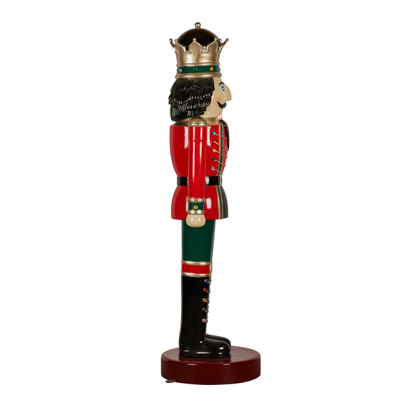 Decorative nutcracker figurine dressed in red and green with a crown on a white background