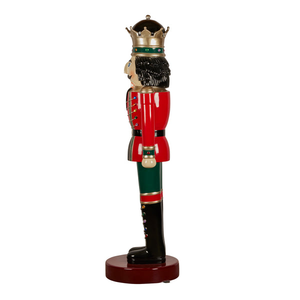 Decorative nutcracker figure dressed in red and green with a crown on a white background